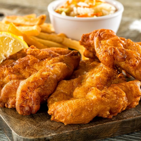 Crispy fried fish and golden french fries with a lemon wedge and coleslaw.